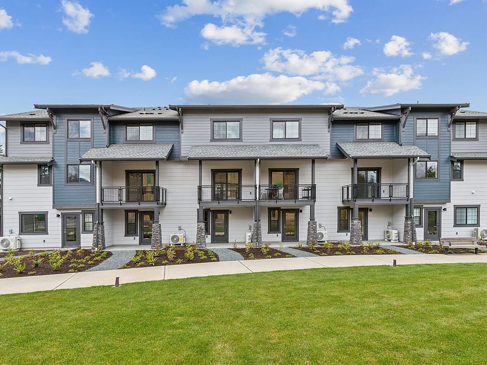 A multi-unit residential building with a grassy lawn in the foreground, set against a backdrop of a