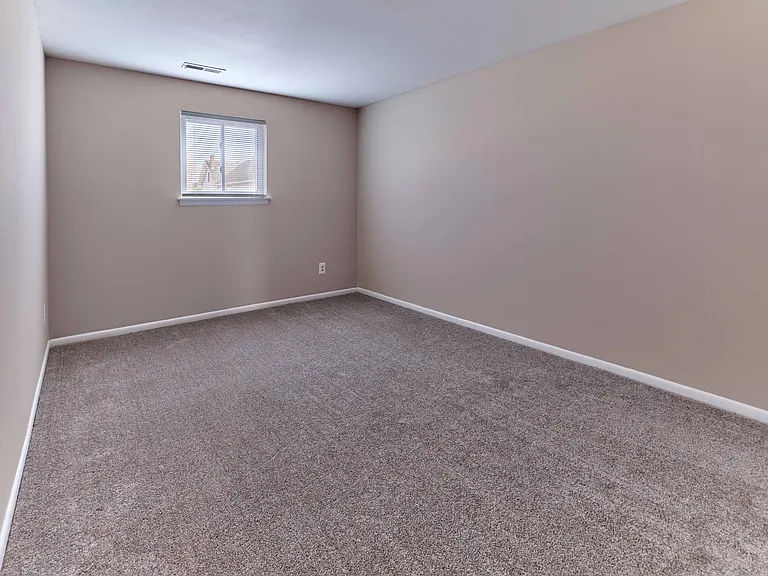 Spacious bedroom with carpet flooring at Village Square Apartments.