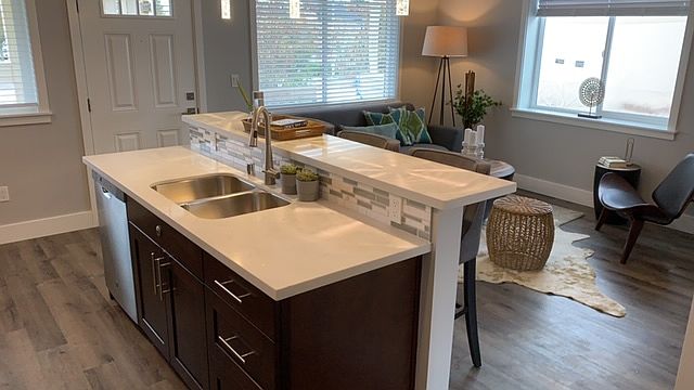 Island Bar with stainless steel sink and whisper quiet dishwasher, quartz countertops and tile backsplash.