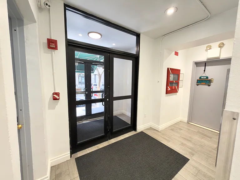 Secured entry foyer with glass doors, durable flooring, and space for mats before heading into the building.