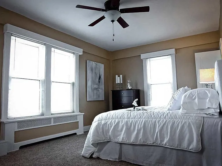 Bedroom with plush carpeting and large windows.