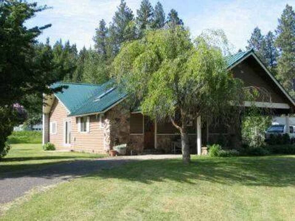 Front view of this craftsman style farmhouse has a decorative stone front with wood siding. Circular driveway with covered carport at entry overlooking the front yard