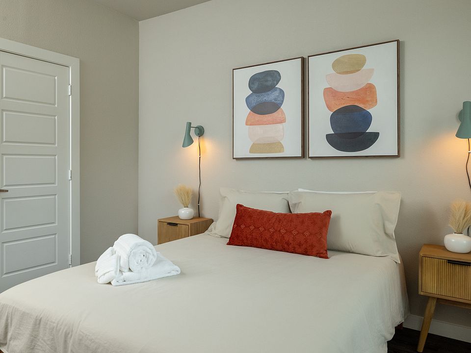 Cozy third bedroom with a queen bed, unique green hanging light fixtures on each side, and plenty of natural light_fresh, stylish, and serene. This bedroom is located upstairs.