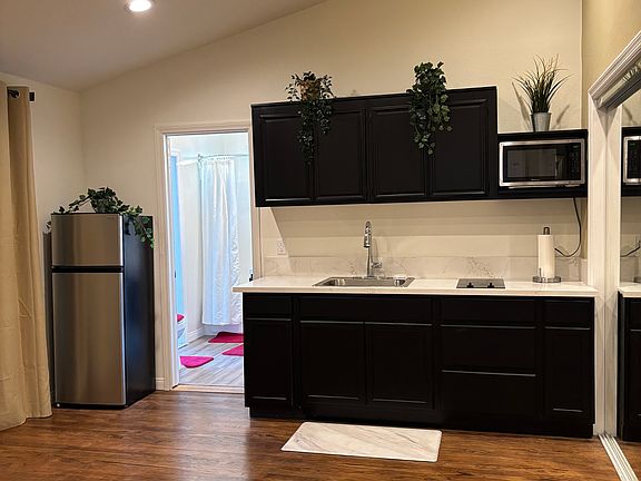 Newly remodeled kitchen with new cabinets, sink, modern faucet, microwave, refrigerator, and beautiful granite countertops, with lighting that can be dimmed under cabinets.
