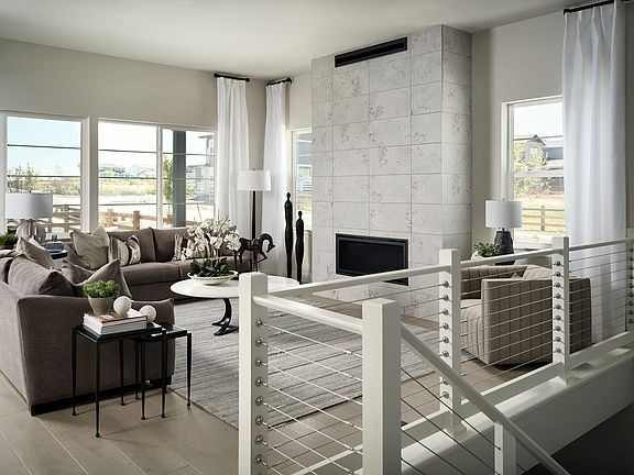 A modern and minimalist living room with a fireplace, large windows, and a mix of neutral-toned furn