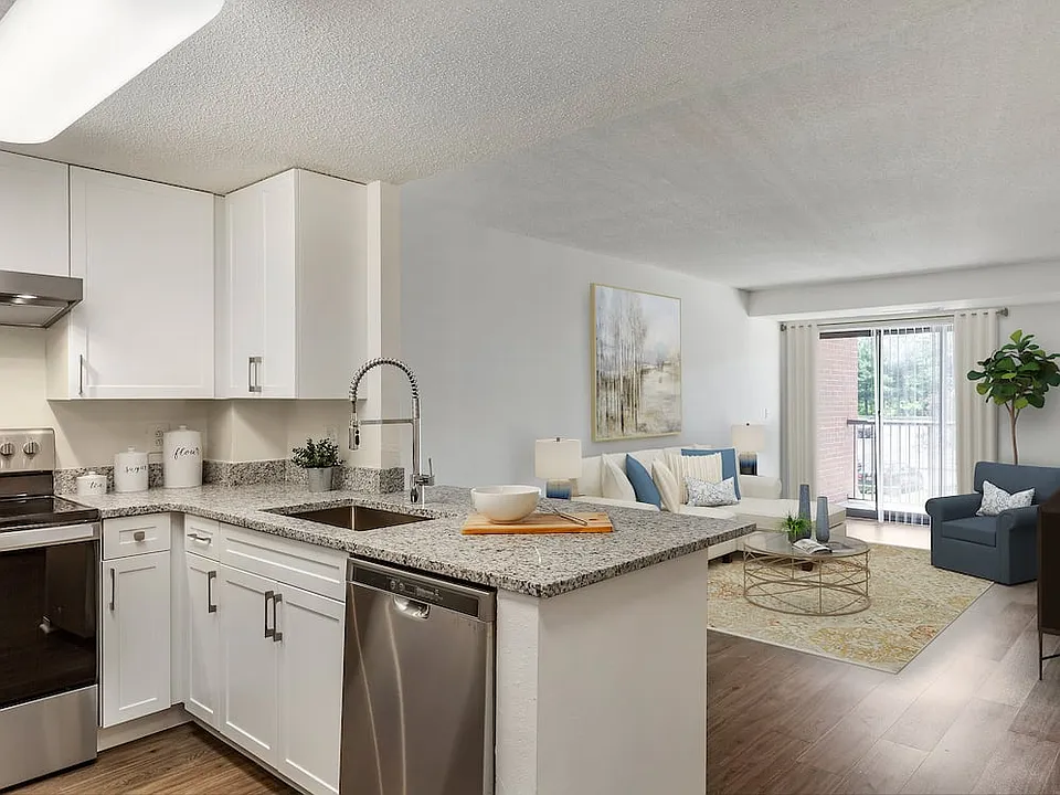 Renovated Package III kitchen and living area with white cabinetry, grey granite countertops, stainless steel appliances, and hard surface flooring
