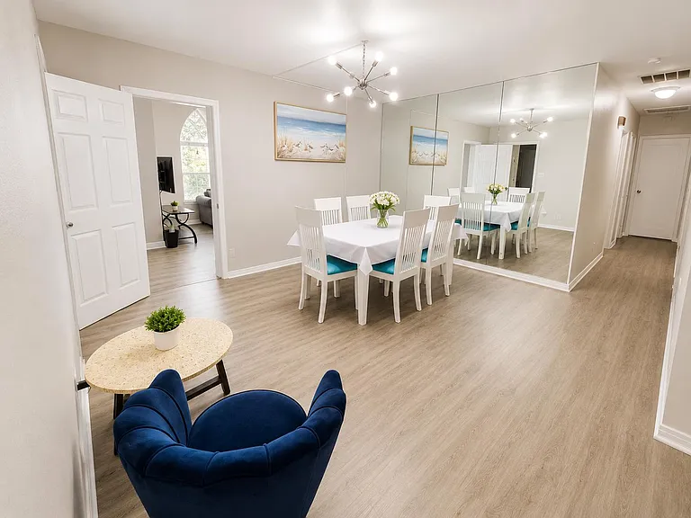 Spacious dining area with a full-size table, statement lighting, and a mirrored wall that enhances the open layout.