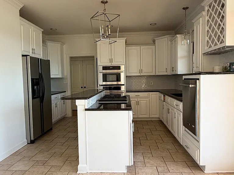 Spacious open kitchen with center island, tile flooring and plenty of cabinet storage.