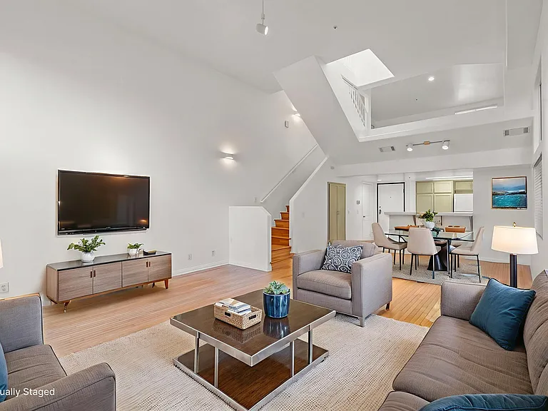 Downstairs living room, dining room, kitchen, bathroom and under stairs closet. Soaring 16 ft ceilings, a central skylight and large windows keep the unit light and bright.