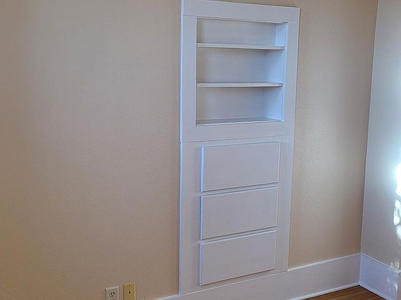 Bedroom with built in drawers and shelves.