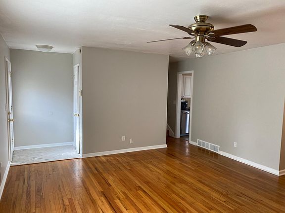 View from front of living room showing entryway, entrance to kitchen, and stairs to bedrooms