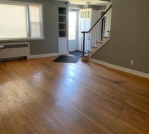 Living room with view of picture window, side window and front door as well as staircase to second floor.
