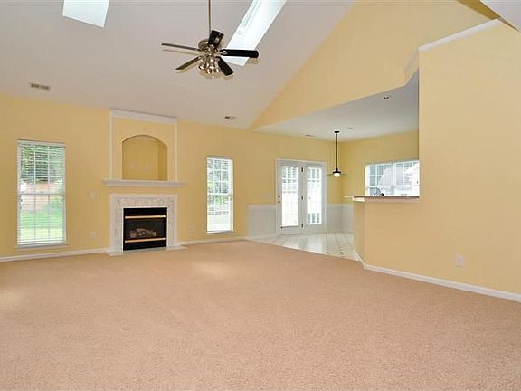 Open, large great room with vaulted ceiling with skylights, gas fireplace