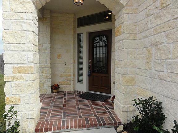 Covered brick front porch shows off the pretty stone facade & upgraded front door