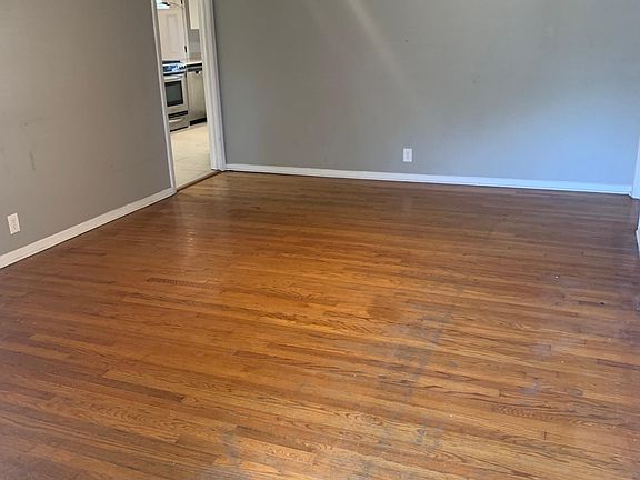 Bright front living area with hardwood floor and ceiling fan.