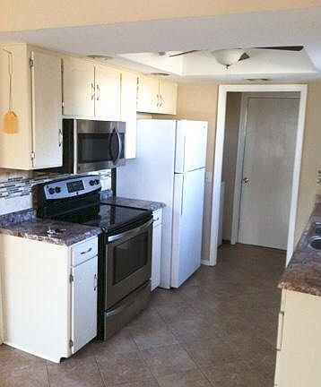 Side view of kitchen. Laundry is just beyond with washer on left, dryer on right. Storage cabinets above both.