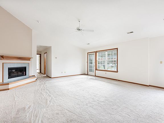 Great Room with vaulted ceiling and doorway to covered front balcony. New carpet