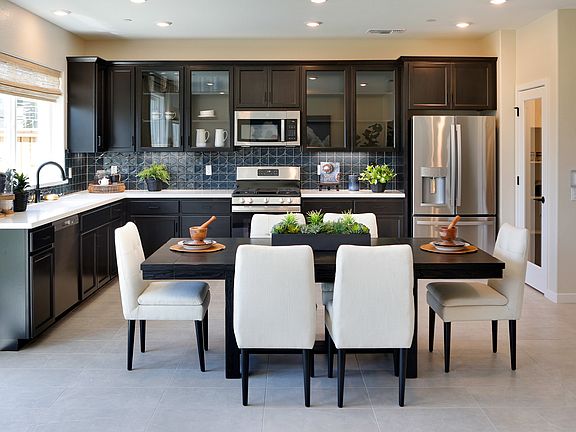 A modern and stylish kitchen with dark wood cabinets, stainless steel appliances, and a dining table