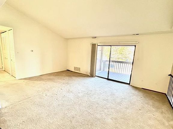 Large living room with vaulted ceiling and slider to balcony patio