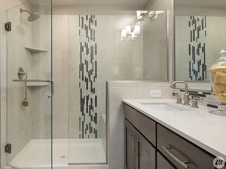 Modern full bathroom featuring a walk-in glass shower, quartz vanity, contemporary fixtures, and stylish tile accents - offering both comfort and functionality.