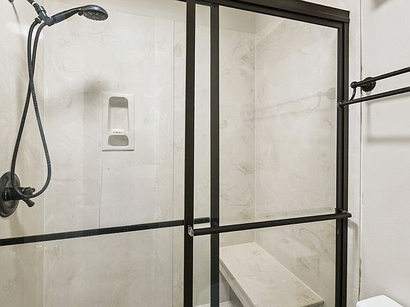 Large shower with handheld shower head and seating area