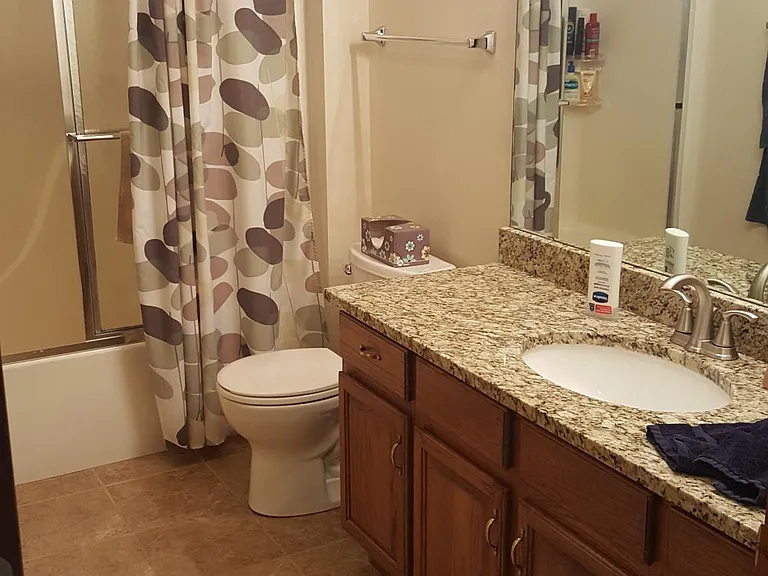 Updated full bathroom with modern vanity, granite top, and bright lighting.