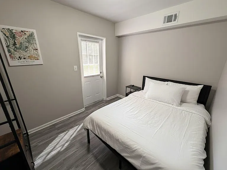 Private bedroom with a full bed, side table, and easy access to an exterior door for convenient entry and natural light.