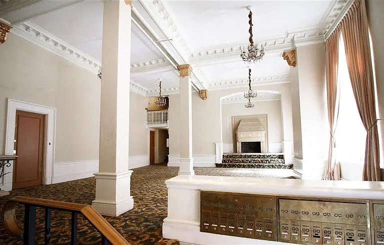 Lobby with a high ceiling, features a large fireplace, a staircase and a chandeliers