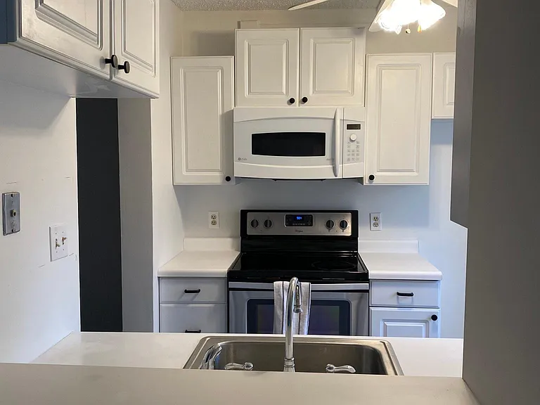 White laminate countertop on white raised panel cabinets. G E Advantage microwave with vent hood inside