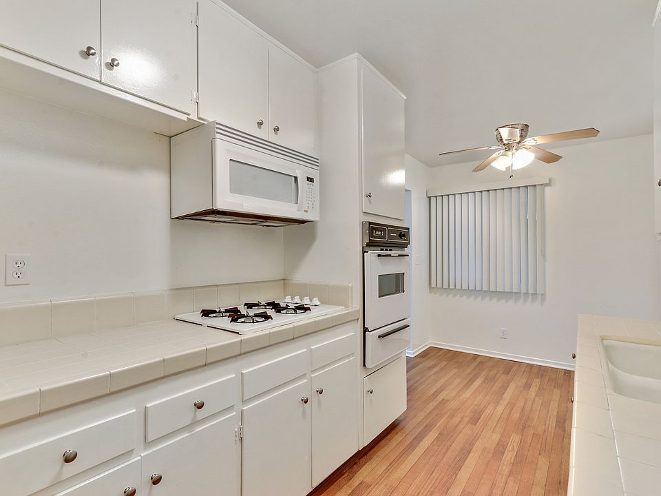 Kitchen with white gas cooktop over microwave, White Oven, Wood Style floors throughout dining area with ceiling fan