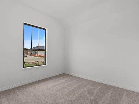 Second bedroom featuring plush carpet, a large window for natural light, and a spacious closet.
