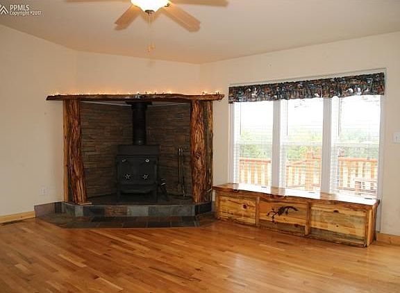 Another view of the stove with custom wood work surround and a custom log wood box to the right that stays with the home as well. Notice the large windows to let in all that natural light.