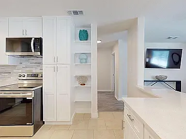 Open kitchen layout with built-in shelving, pantry storage, and clear sight lines to the living area