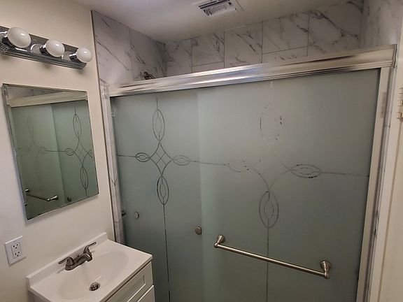 Enjoy this beautifully custom porcelain tiled to the ceiling shower with new tasteful frosted privacy sliding doors