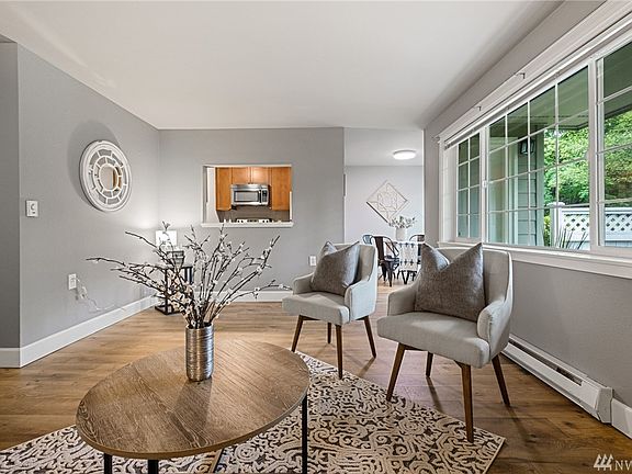 Standing near the fireplace you can look through to the kitchen and the dining room. Peek out the windows at all the trees. 