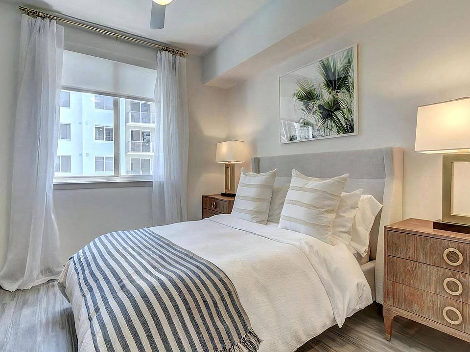Interior Bedroom Featuring Palm Wall Art, Sheer Curtains, and Upholstered Headboard