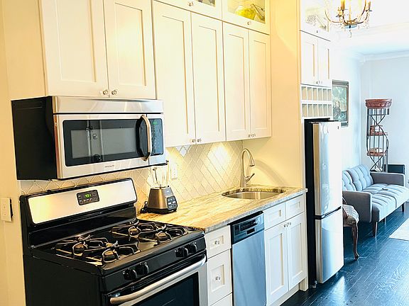 Beautiful kitchen includes dishes, silverware ,pots, pans blender , coffee pot.