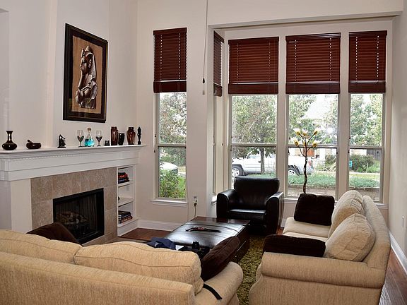 Elegant living room with soaring ceiling and wood flooring with matching blinds