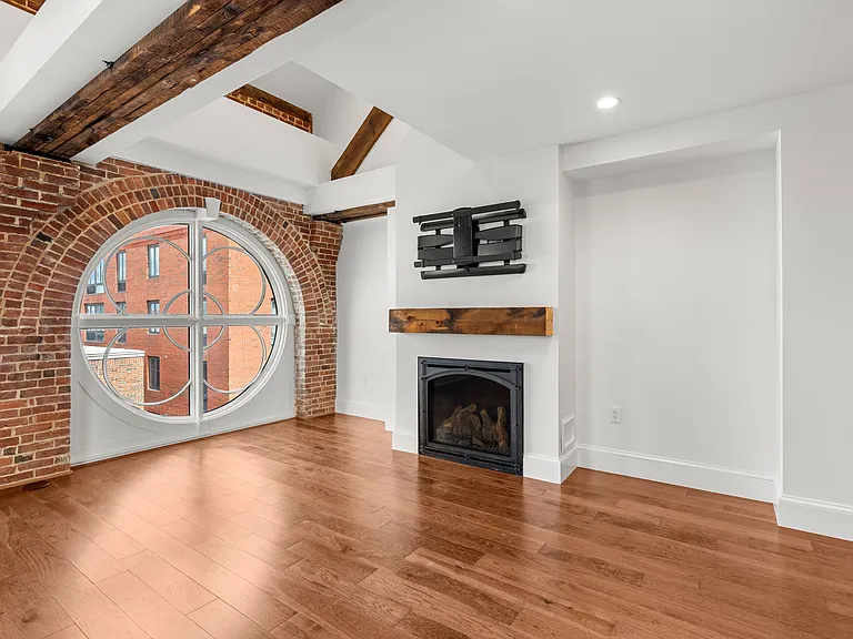 Living room with vaulted ceilings, exposed beams, high end fireplace, very full swivel expensive TV mount