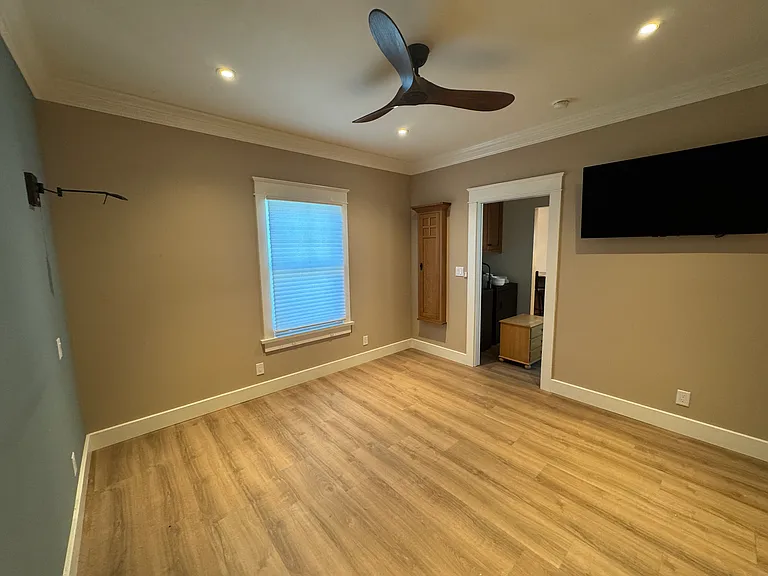 Bedroom with built-in ironing board in customer oak cabinet and a 48" LG TV