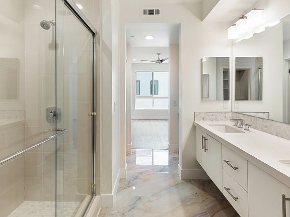 Master bathroom with dual sinks, marble floors, and a walk-in shower