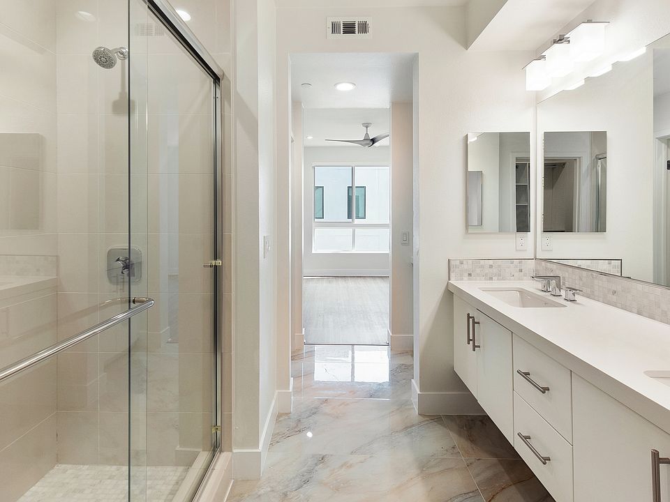 Master bathroom with dual sinks, marble floors, and a walk-in shower