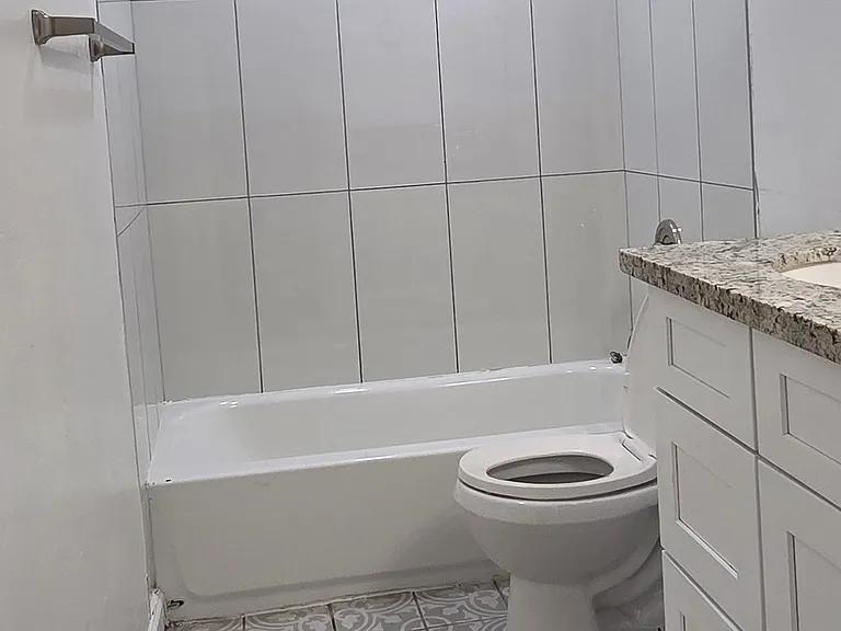 The shower has been tiled all the way up to the ceiling.
