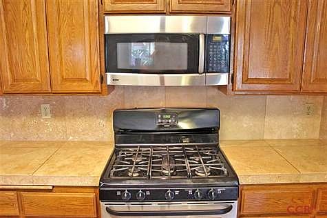 UP CLOSE OF THE STAINLESS APPLIANCES AND GORGEOUS TILE COUNTERS