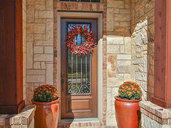 The entry of the hone has a large wood pillars as you approach the entry and glass front door is  decorated with wrought iron accents.