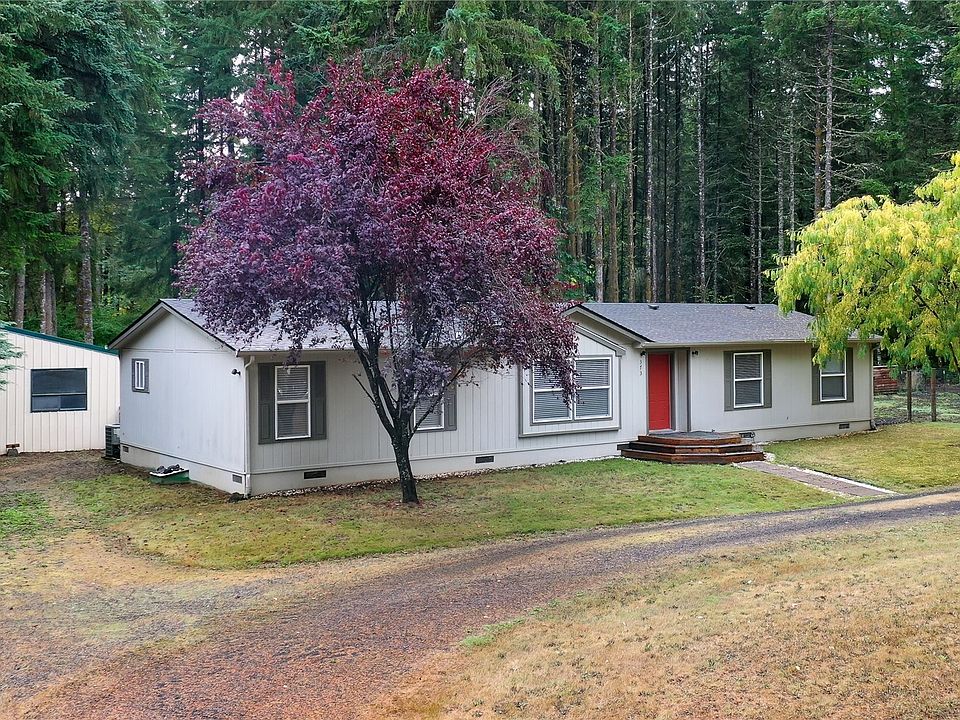 Drone view of front of home and property, note circle driveway and tall pines behind. >