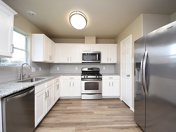 Crisp, clean, and oh-so-chic! Loving the vibe in this kitchen with its stunning white cabinets. It's all about that fresh look! The elegant kitchen also boasts stainless steel appliances, adding a touch of modern sophistication.