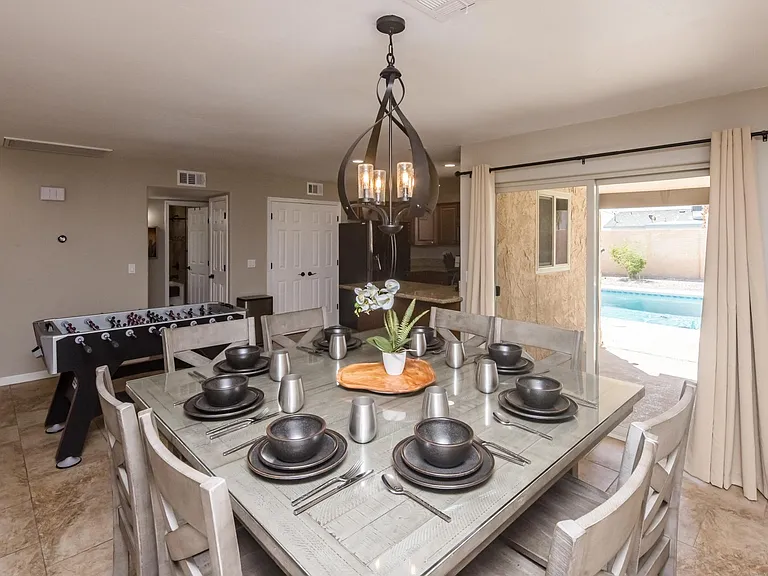 Spacious formal dining area with modern chandelier and direct sliding door access to the private backyard and pool.