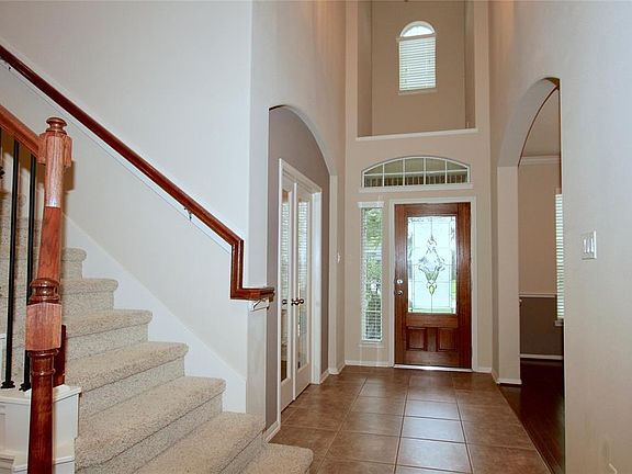 The Two Story Foyer features tile floors and arched doorways to the dining and study along with a wrought iron spindle staircase.