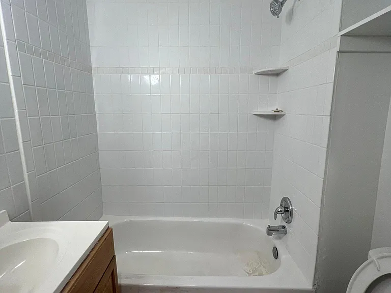 Bright, clean bathroom with updated tile surround, bathtub, and extra built-in storage.